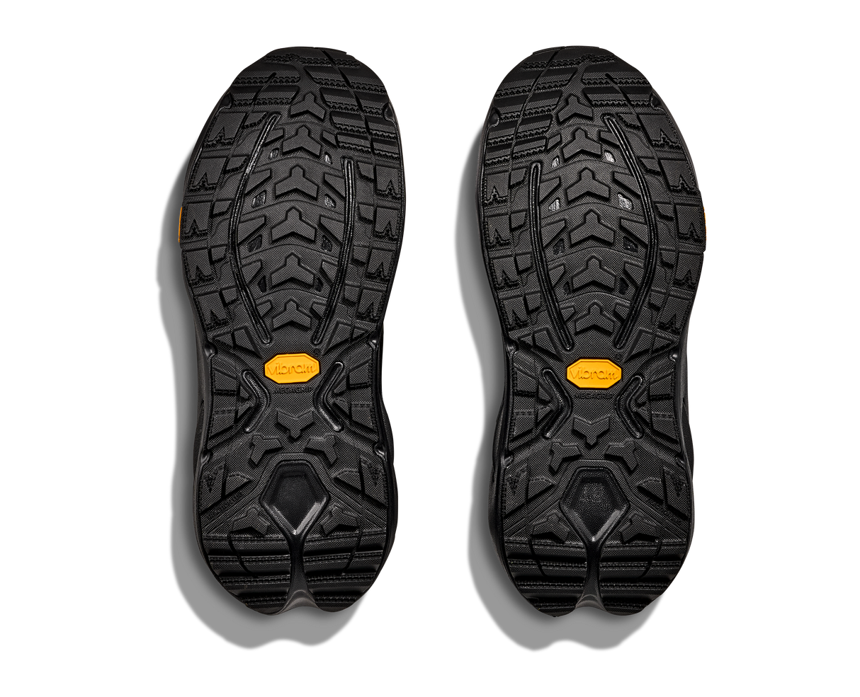 Black shoe soles with yellow accents on a white background