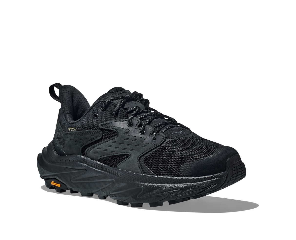 Black athletic shoe with orange Vibram logo on sole on a white background