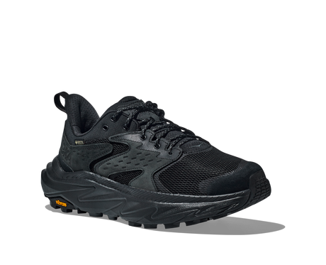 Black athletic shoe with orange Vibram logo on sole on a white background