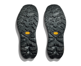 Close-up of black shoe soles with tread pattern and orange Vibram logo on a white background