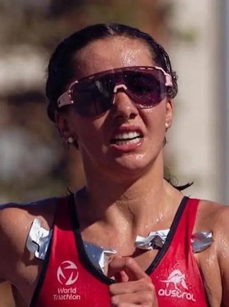 Athlete wearing sunglasses and a red sports bra with visible branding during an event.